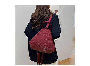 Model wearing a burgundy checkered dumpling shoulder bag in a minimalist interior setting