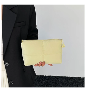 Close-up of quilted cream yellow nylon clutch bag with padded texture and zipper detail