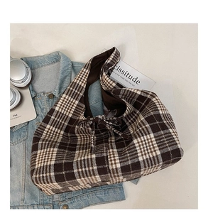Brown and white checkered fabric tote bag with drawstring on blue denim jacket