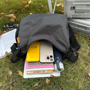 Détail de la capacité intérieure du sac à carreaux montrant des cahiers et une gourde