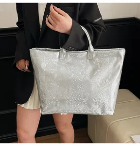 Macro detail of silver snake embossed tote bag with metallic shine and white TOTE BAG print