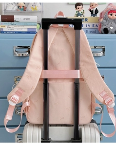 Pink backpack with bow prints showing back straps and luggage trolley sleeve feature