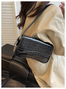 Detail showing the glossy black crocodile pattern leather texture on a vintage baguette bag