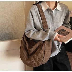 Vista detallada del bolso tote de cuadros marrones que muestra la textura y el estilo al hombro