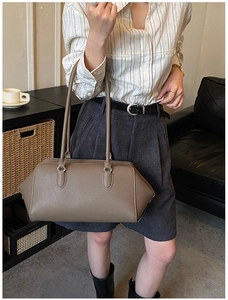 Elegante borsa bowling in pelle tortora in un interno minimalista con mobile nero
