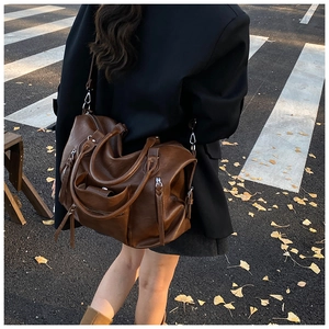 Deep brown PU shoulder bag with metal zippers shown in a street style fashion setting