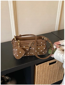 Detail der braunen Vintage-Umhängetasche mit Punkten, Herzanhänger und Taschen-Design