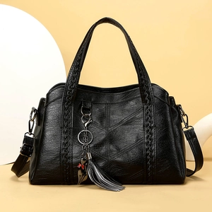 Black pebbled leather tote bag with woven handles, tassel cat charm and long strap