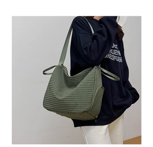 Detail of dark green checkered tote bag with wide strap on model in minimalist setting