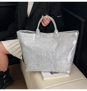 Close-up of a grey snakeskin textured tote bag with white TOTE BAG text detail