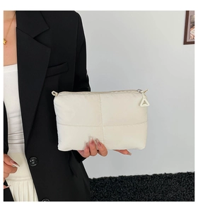 Close-up of white quilted cloud makeup bag with soft texture held by a model