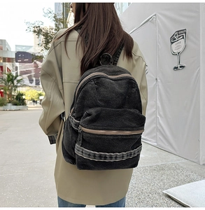 Détail d'un sac à dos vintage en denim noir délavé avec poche avant et bretelles robustes