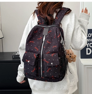 Détail d'un sac à dos noir avec nœuds rouges, pois et breloque peluche chiot marron mignonne