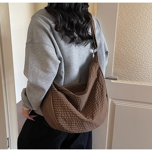 Primer plano detallado del bolso hobo de cuadros marrones con textura de tela rugosa