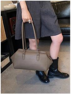 Dettaglio di una borsa bowling grande in pelle beige con superficie testurizzata a grana litchi