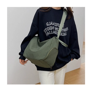 Detail of green checkered dumpling bag showing woven canvas texture and wide strap