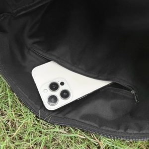 Gros plan de la poche intérieure zippée montrant une grande capacité avec un smartphone