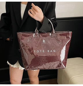 Close-up of a burgundy snake-pattern glossy tote bag with white TOTE BAG lettering detail