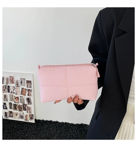 Detail of pink quilted puff makeup bag in soft nylon material held by a model