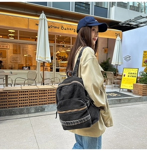Détail du sac à dos en denim noir délavé avec double fermeture éclair et style rétro