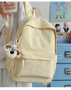 Detail of cream yellow backpack featuring white bow embroidery and cute puppy plush pendant