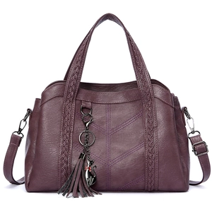 Deep purple faux leather tote bag with braided handles and a cat charm on a white background