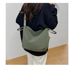 Detail of green checkered canvas dumpling bag shown on model for a casual styling look