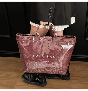 Close-up of snake skin textured tote bag in glossy deep wine red with white lettering