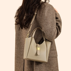 Détail du sac seau en cuir grainé taupe avec boucle dorée et bandoulière amovible