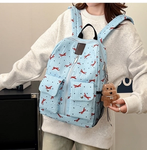 Détail du sac à dos matelassé bleu clair avec motifs nœuds rouges et breloque ours