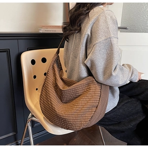Bolso hobo a cuadros marrones con correa ancha de hombro usado por modelo para uso diario
