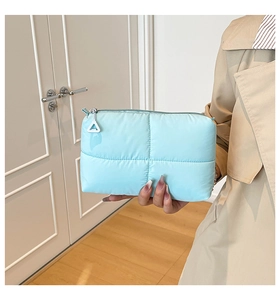 Detail of light blue quilted makeup bag with soft bubble texture and metal zipper