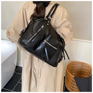 Detail of black PU leather shoulder bag with silver zippers and long leather tassels