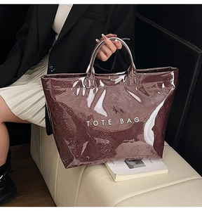 Close-up of a red glossy PVC tote bag featuring snakeskin texture and white logo text