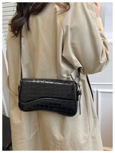 Detail of black crocodile embossed leather shoulder bag with gold adjustable buckle strap