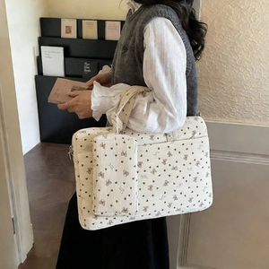 Detailed view of cream corduroy shoulder bag with purple bow and heart floral patterns