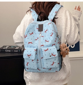 Sac à dos bleu clair texturé avec nœuds rouges et breloque chiot marron mignonne