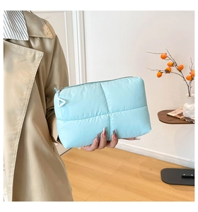 Detail of light blue quilted bubble makeup bag with white triangle zipper charm