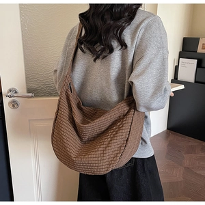 Bolso bandolera de cuadros marrones mostrado por una modelo en un ambiente acogedor