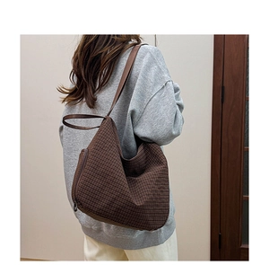 Brown plaid oversized hobo bag on model showing stylish shoulder carrying style