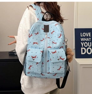 Vue détaillée d'un sac à dos bleu clair avec motifs nœuds et charm ours en peluche