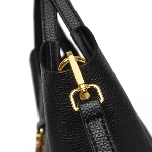 Gros plan d'un sac à main noir en cuir grainé avec un fermoir pivotant en métal doré