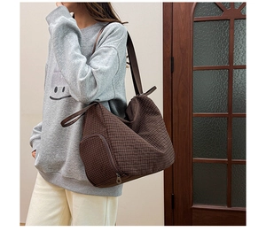 Close-up of dark brown plaid tote bag showing soft fabric texture and zipper pocket details