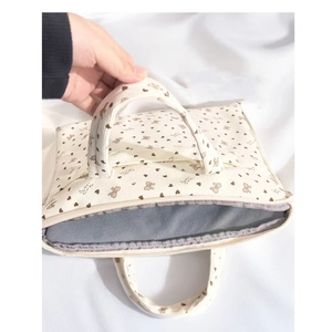 Detail view of corduroy shoulder bag showing brown heart bow print and sturdy handles