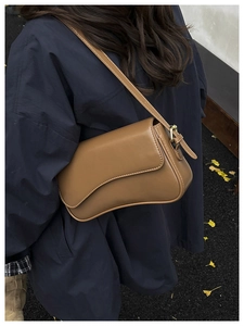 Brown vintage baguette bag with asymmetrical flap on model in autumn street setting
