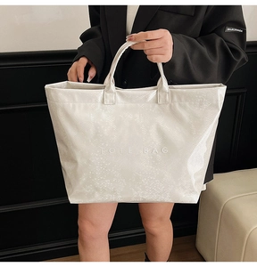 Detail of white embossed snakeskin pattern and TOTE BAG lettering on glossy tote bag
