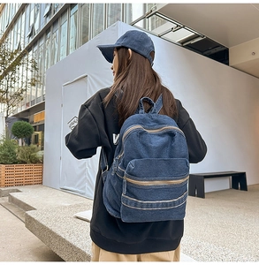 Détail d'un sac à dos en denim bleu foncé avec double fermeture éclair et style urbain