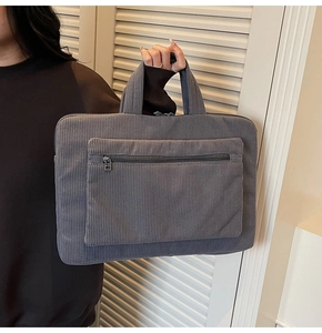 Detail of dark gray corduroy laptop bag with vertical texture and zip pocket