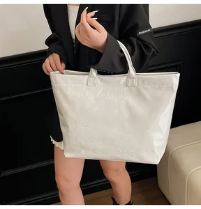 Macro detail of white tote bag with glossy snakeskin texture and embossed lettering
