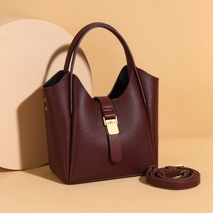 Vue détaillée du cuir grainé bordeaux et du fermoir doré de ce sac seau élégant